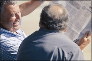 Two men laughing at something they see in the newsletter.